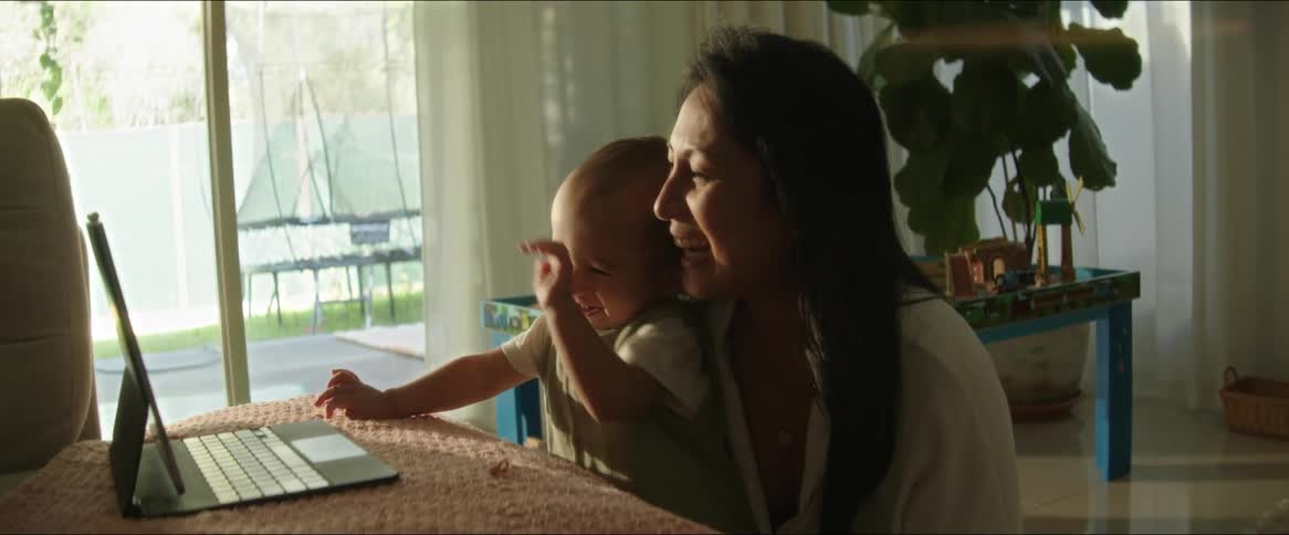A clip of a mother and kid playing in front of a tablet