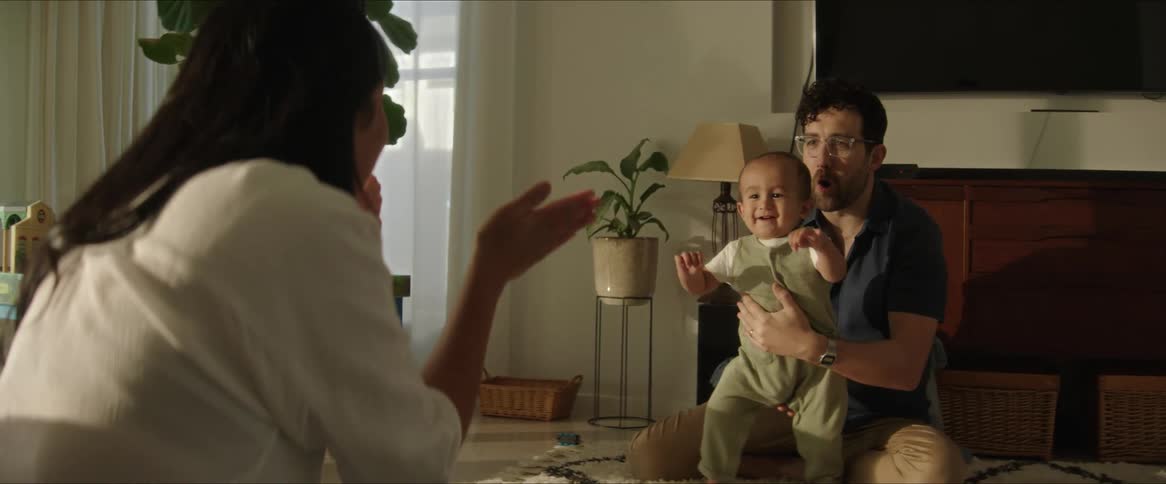 Father and mother sitting on the living room rug playing with their little son