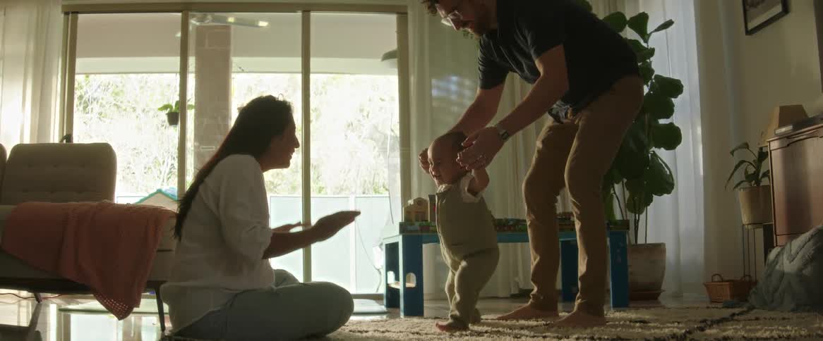 Father and mother teaching their little son to walk