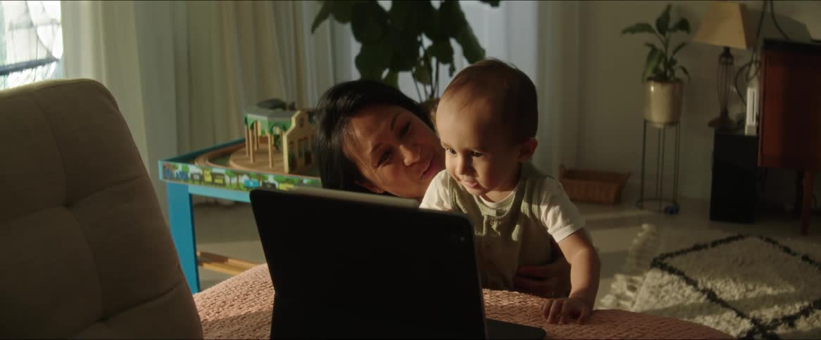 A mother talks with her baby as they watch a tablet