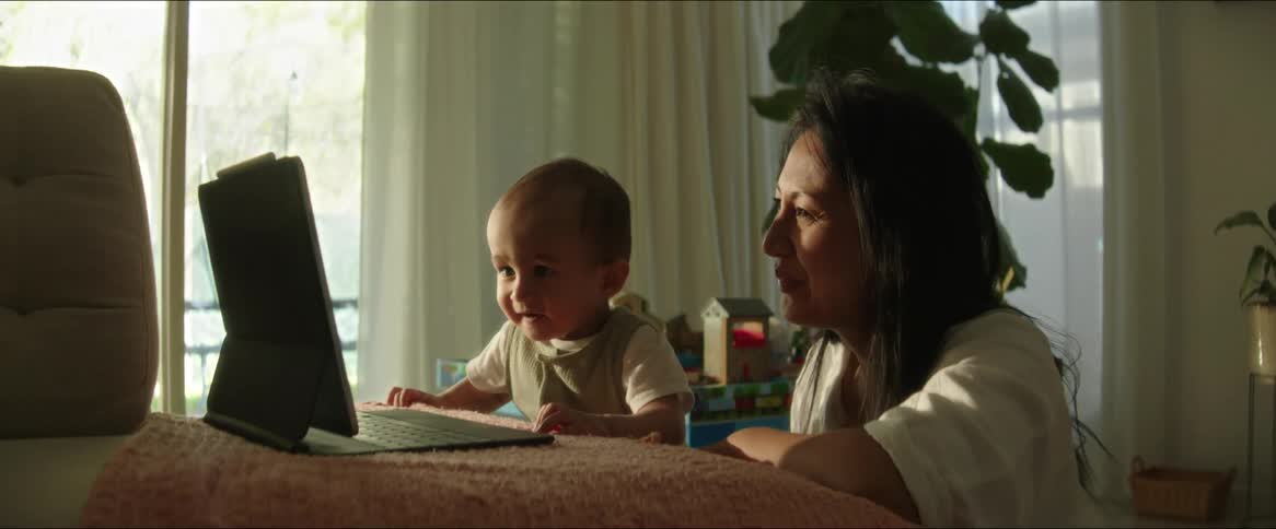 A mom shows her baby something on the laptop