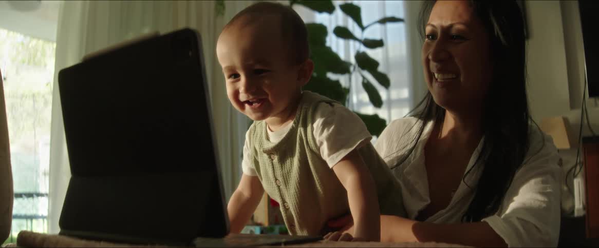 A mom shows her baby something on a laptop