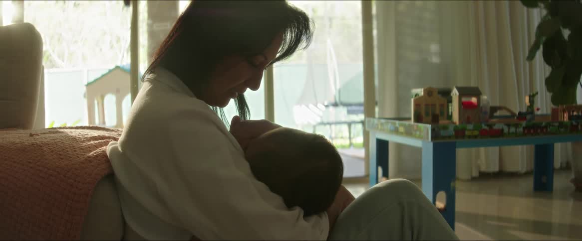 Mother sitting in the living room with her baby son in her arms