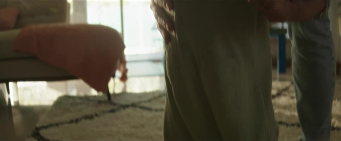 A father teaches his son to walk on a rug in the living room