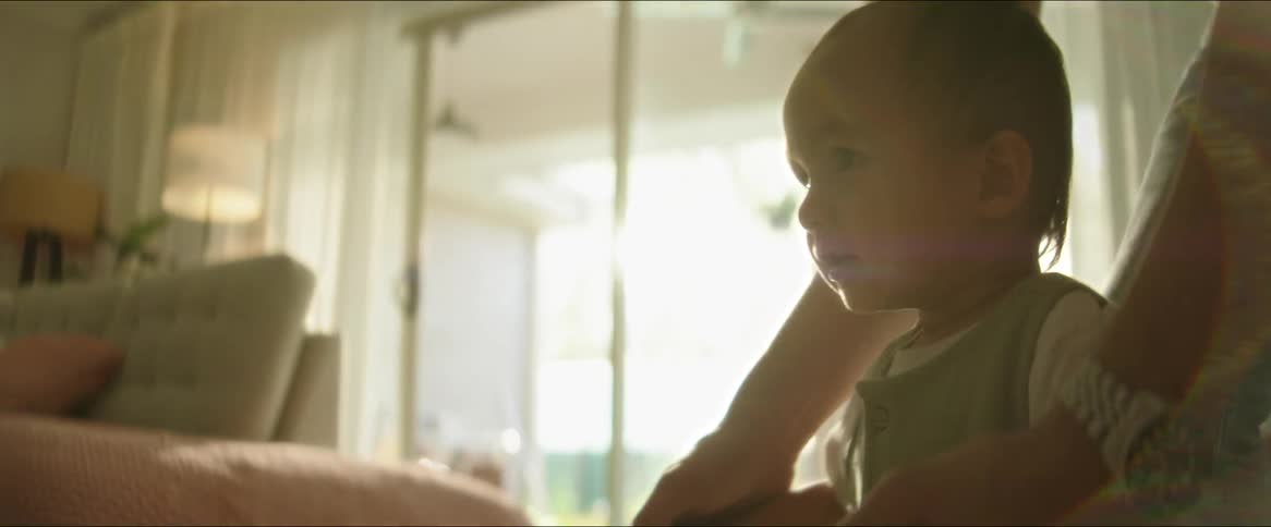 A parent holds a babys hands as he learns to walk in a living room