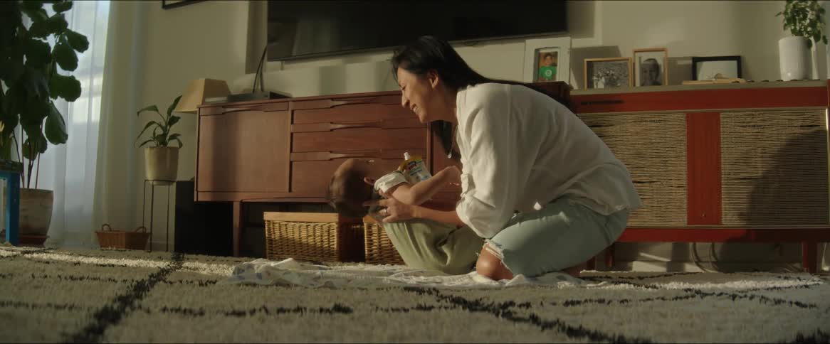 Mother places her baby on the living room rug