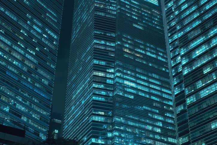 Buildings at night with office window lights turning on at the same time