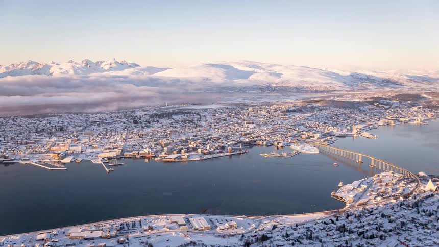 Panorama of an urban city surrounded by mountains and covered in snow and with a sea canal in the middle