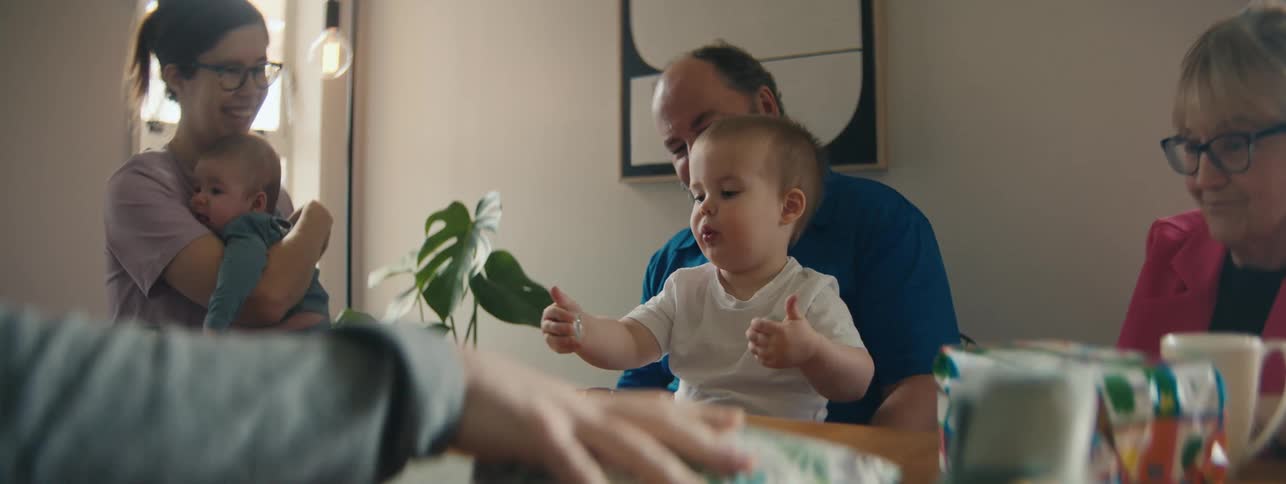 Baby learns how to do thumbs up from his family before receiving a gift