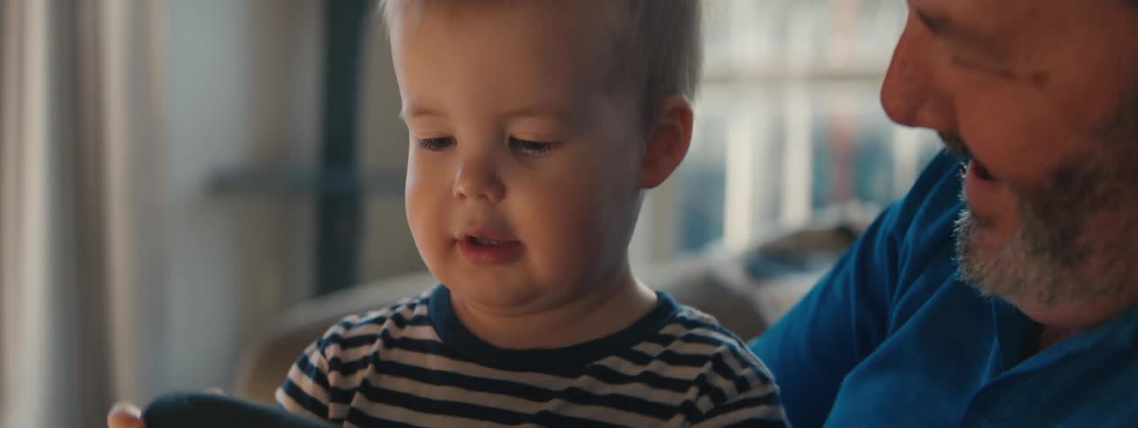 Grandfather encourages grandson in playing with an electrical device