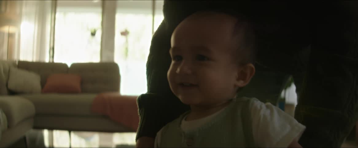 Father helps his toddler walk across the carpet in his living room