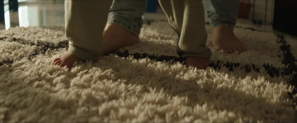 A parent is walking with their baby on the carpet