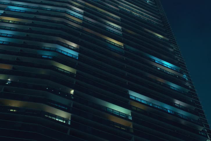 The colorful window lights of a highrise building turn on and off in the building over time