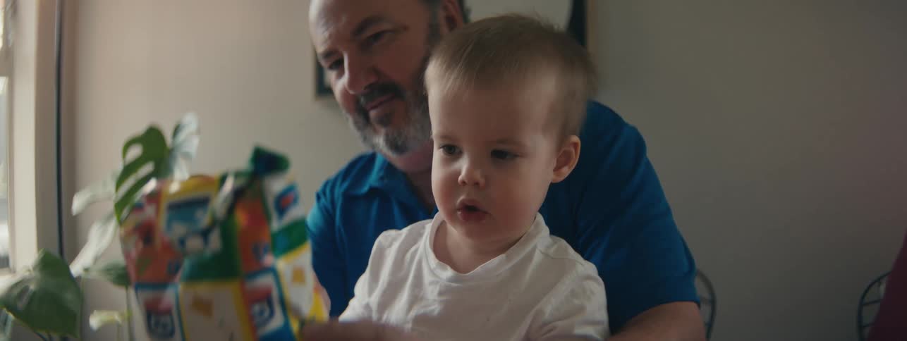 Grandparents watch their grandchild examining a bag of merchandise