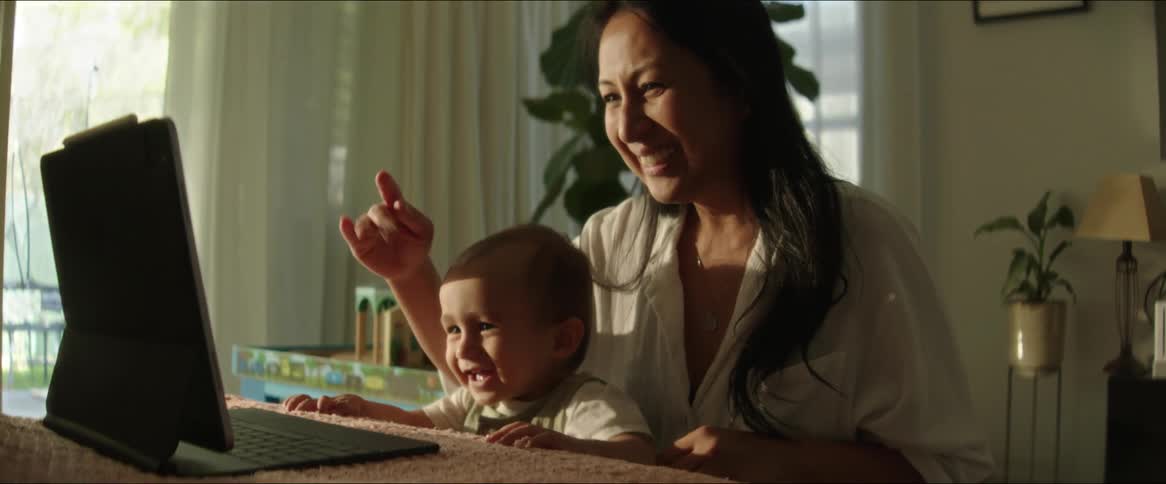Mother with her little son smiling and waving goodbye while interacting with a laptop
