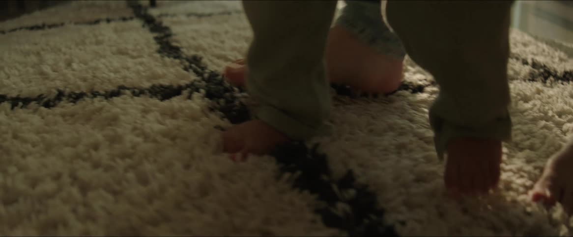 Feet of an adult and a small child walking together on the carpet