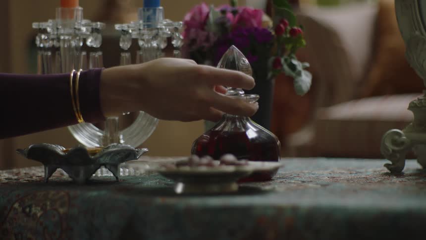 Hand placing a jar with liquid on top of a table