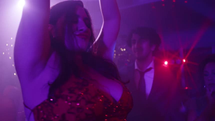 Two women dancing in the center with people around watching in a party atmosphere