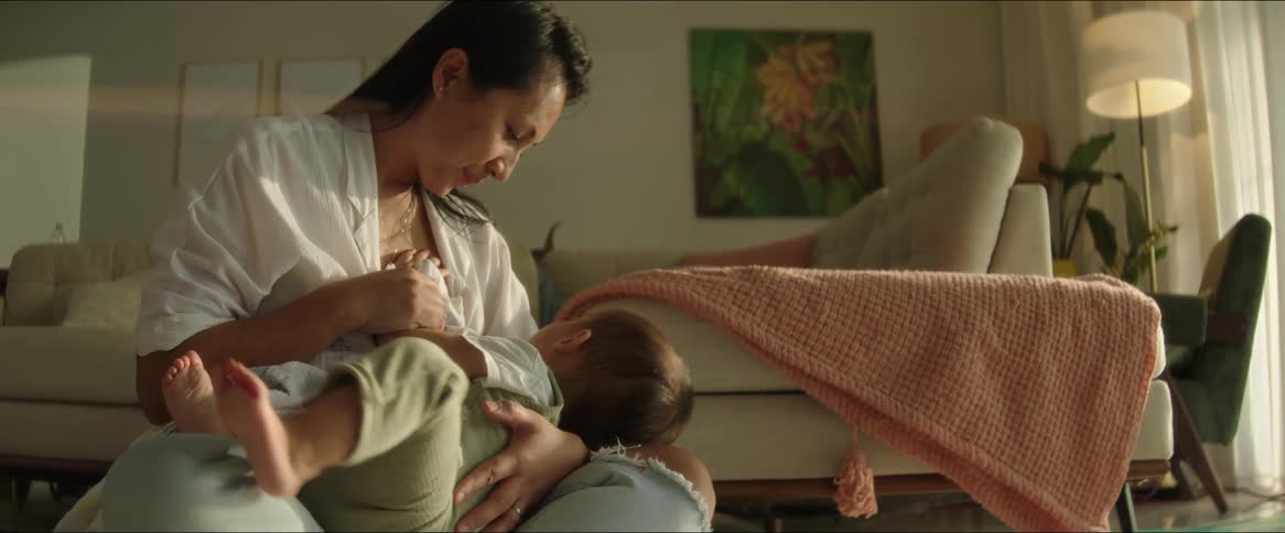 Mother sitting on the living room rug and breastfeeding her baby