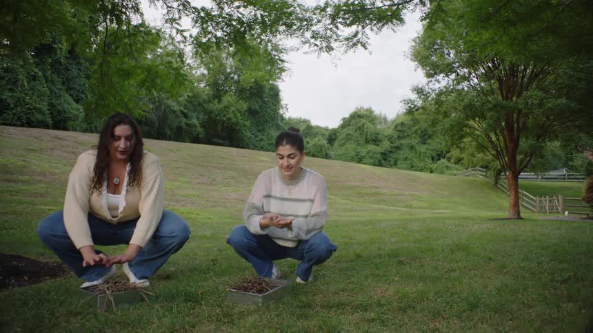 People gathering twigs lie back in a field near a fenced pasture