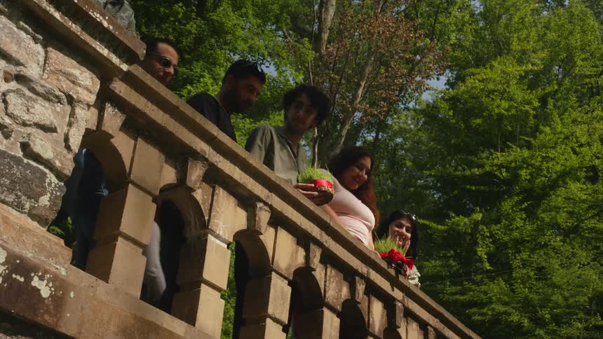 Group of friends leaning on cement railing with trees in background
