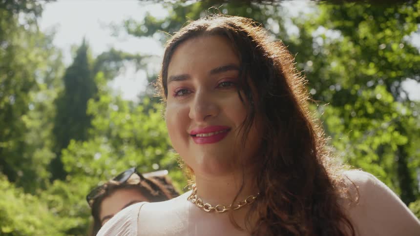 Portrait of a woman with her friends behind her while smiling in a natural setting surrounded by trees
