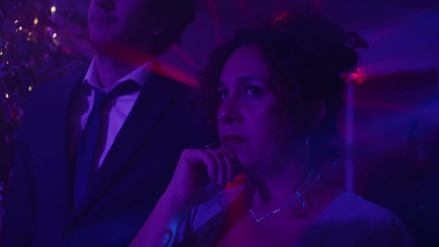 Woman and a man at a party standing and watching