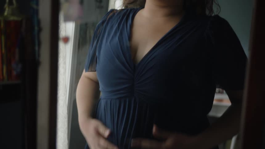 A white teenage girl primps her dress while looking into a mirror