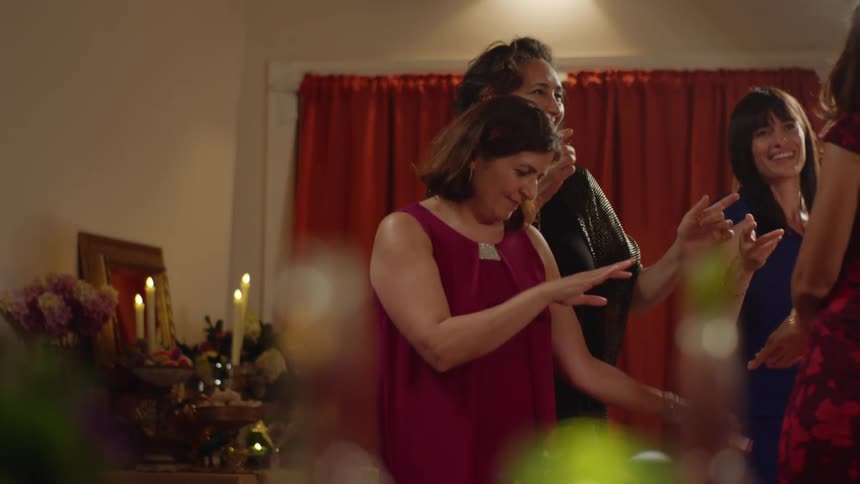 Four women in living room decorated with candles dancing