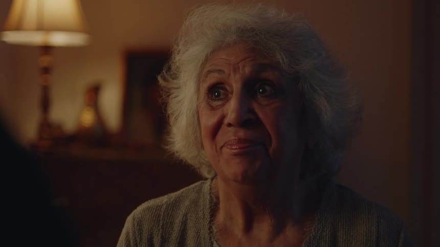 Elderly lady sitting in a room at night looking with happy facial expression