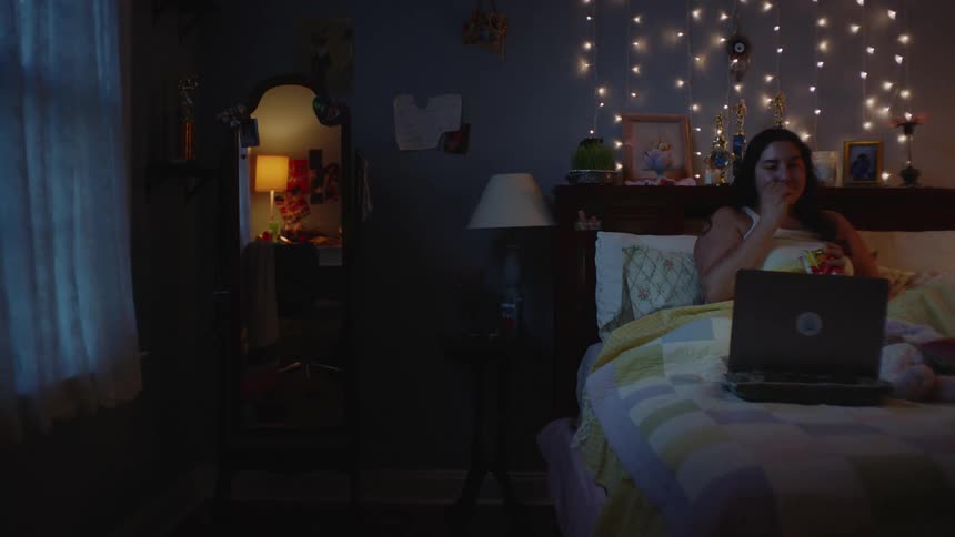 A clip of a lady watching a movie on the bed with her laptop