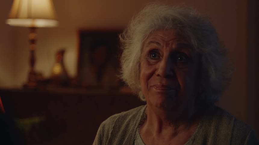 Elderly woman sitting in living room at night