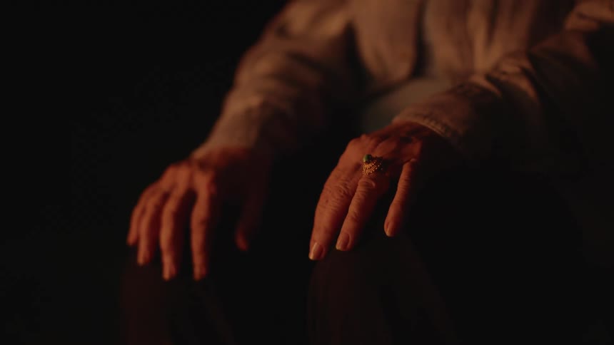 Hands of an elderly woman sitting in an open air environment at night