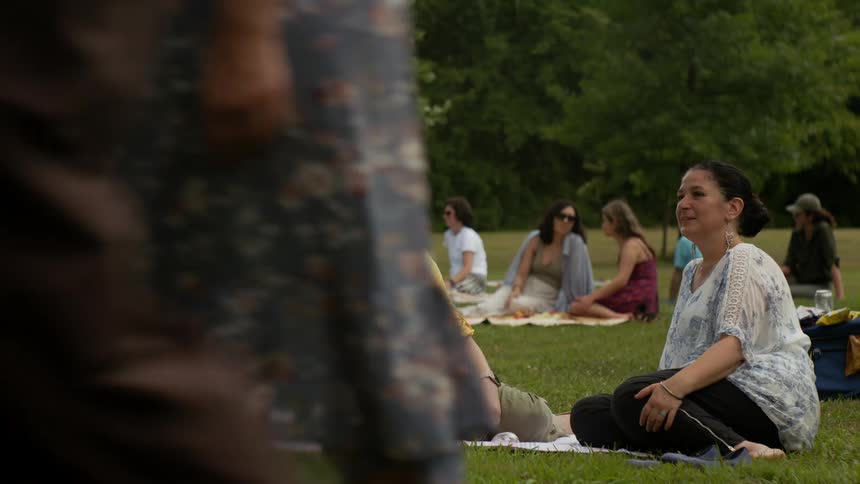 Group of women sitting in a grassy garden talking