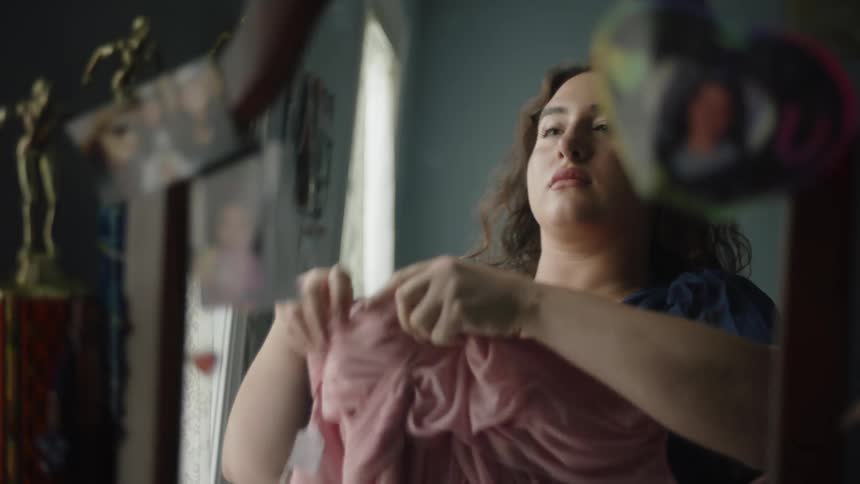 Woman trying on a pink dress in front of a mirror