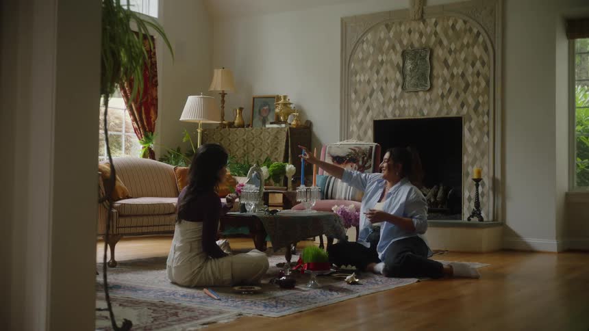 A clip of two females in the living room arranging some flowers on the tables
