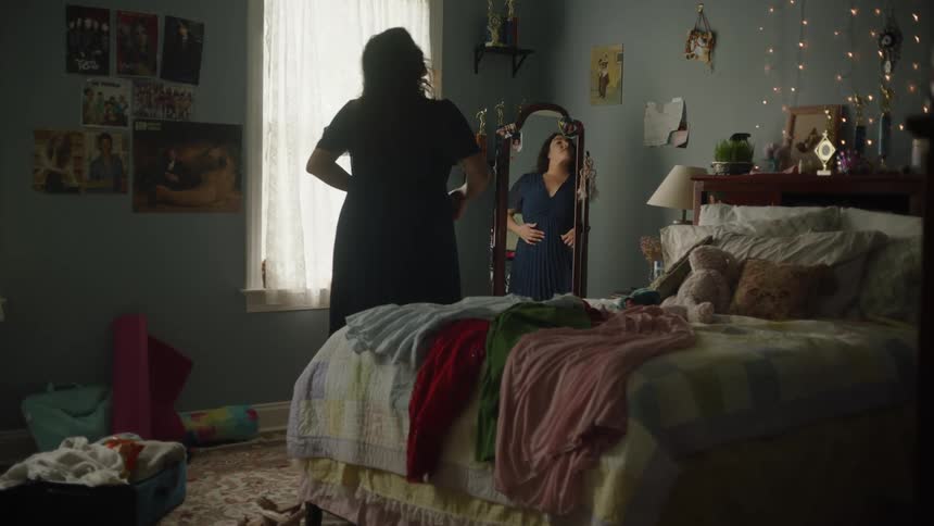 Woman in bedroom looking at herself in mirror
