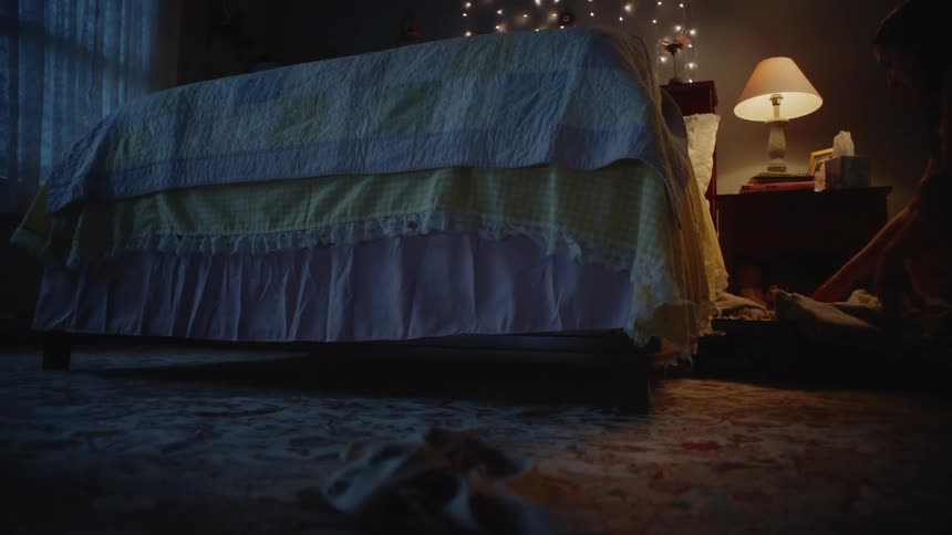 Woman taking off her clothes throwing them on the floor and lying down on the bed