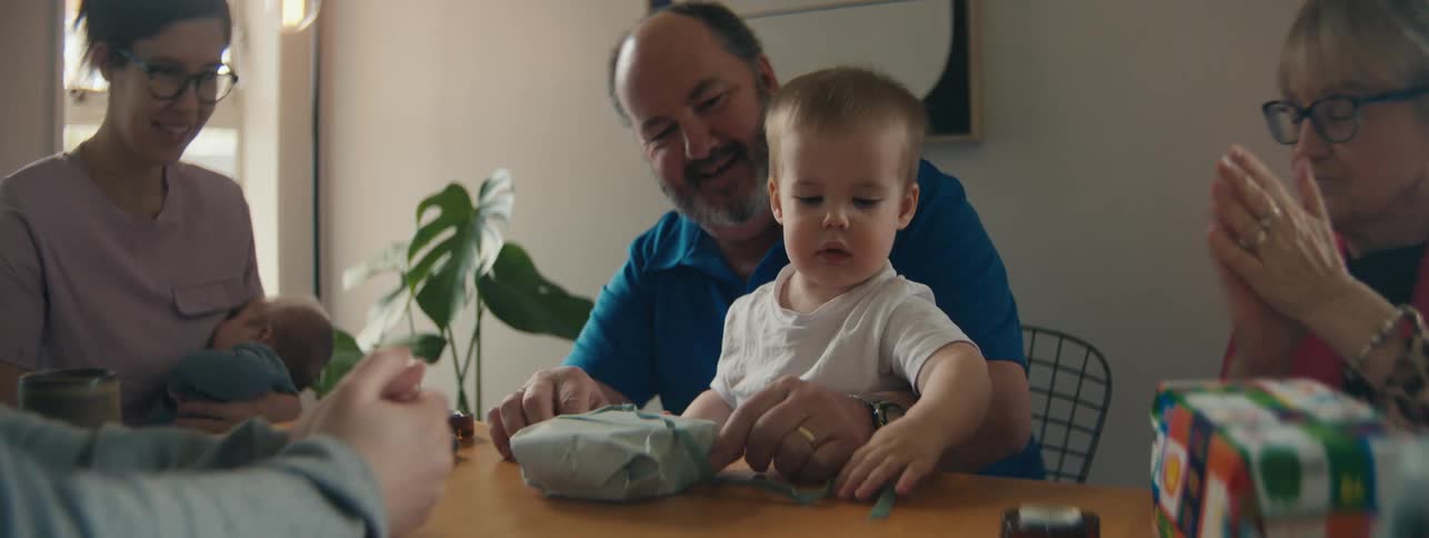 Family gathered at the table with a small child playing