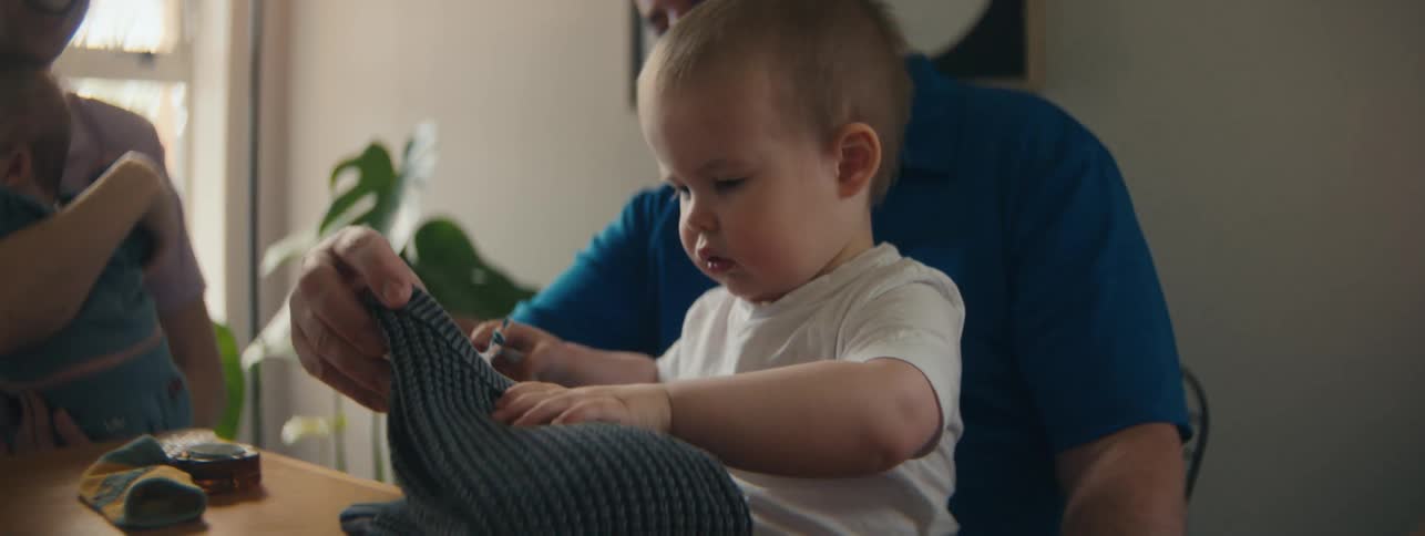 Little child sitting at table with his family receiving gifts