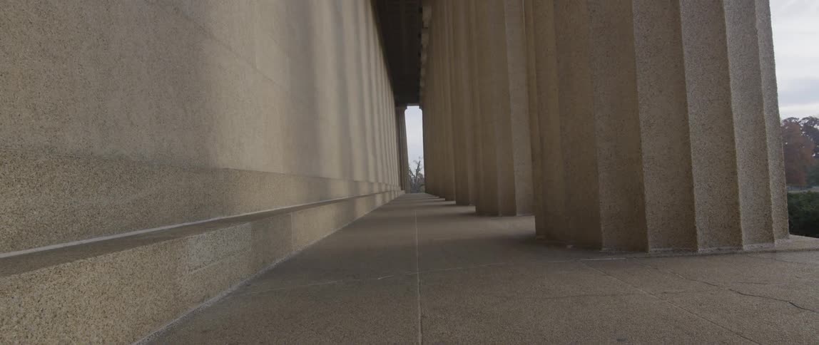 A corridor between a wall and large cement pillars