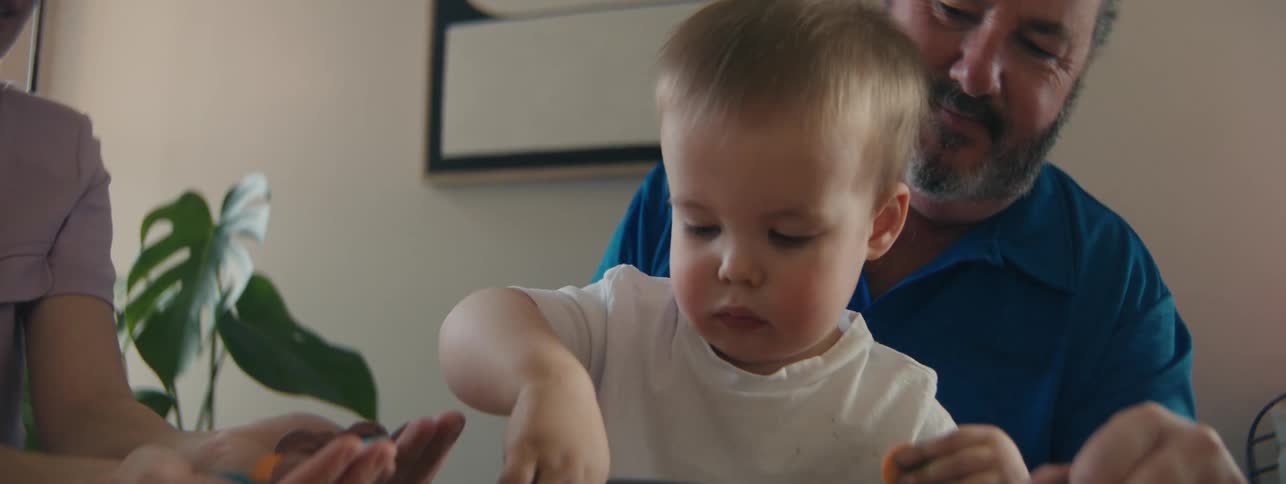 Child sitting at table playing with father and mother next to him