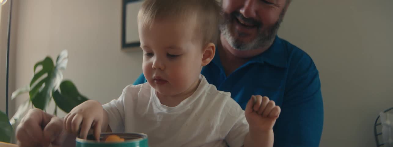 A grandfather watches his grandson play with candies