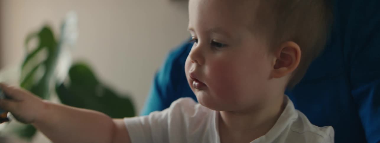 A father helps his toddler shake and play with metal containers