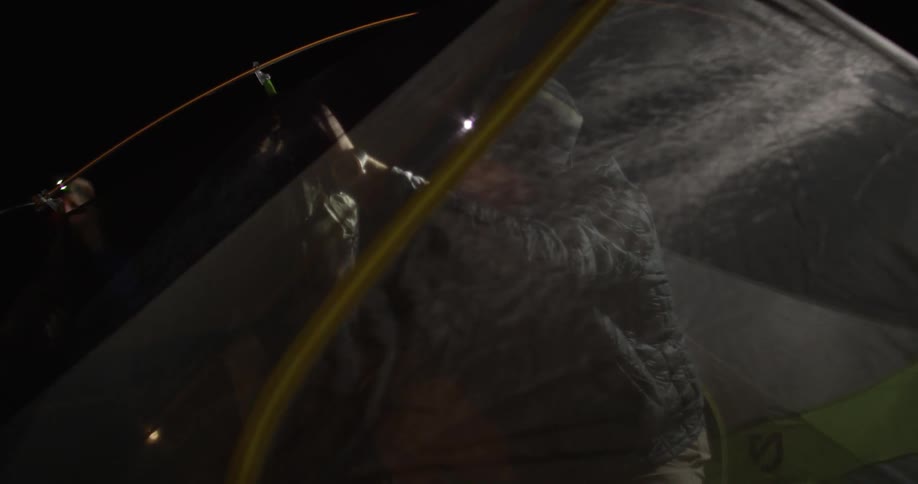 A man hangs up something inside a tent