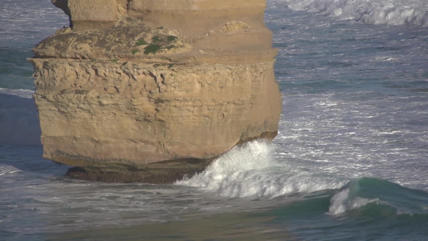 Very large rock on a beach with waves crashing upon it