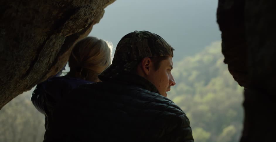 A man sits with his arm around a woman as they admire a view