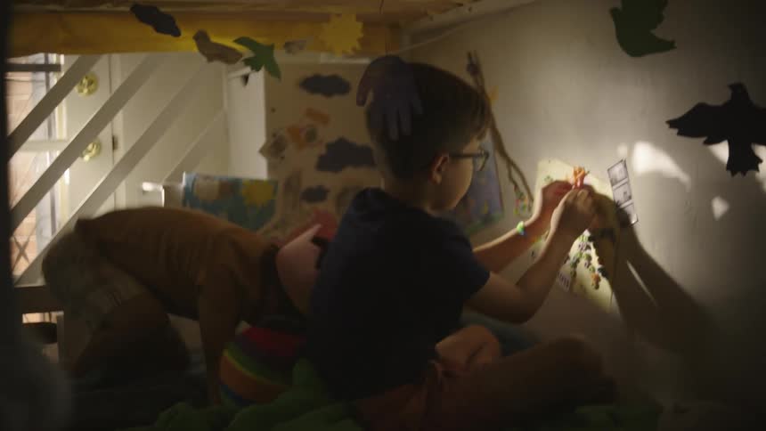Two boys inside a room with one of them jumping around playing