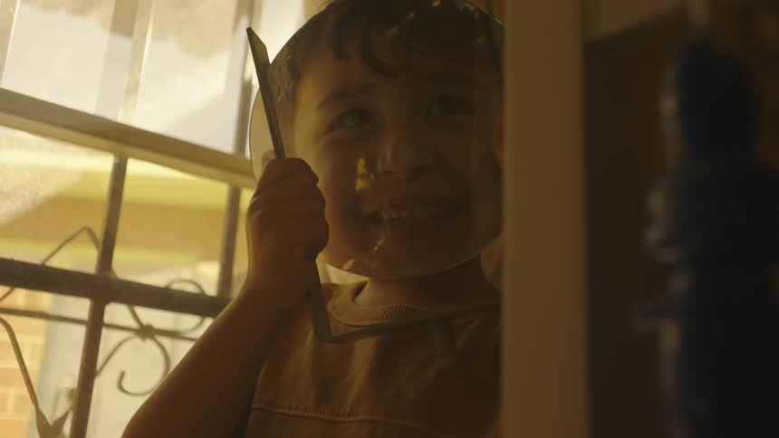 Glass held by child while at home magnifies the childs face