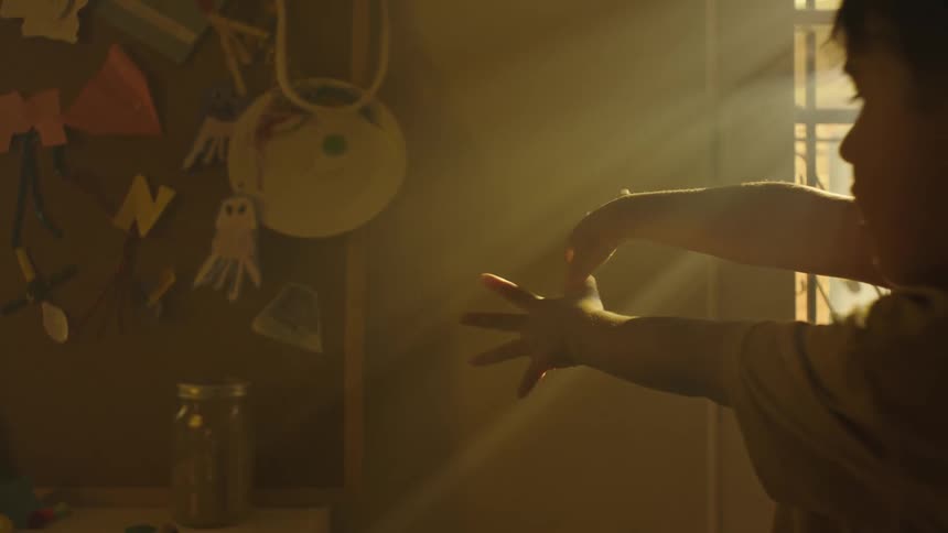 Boy with his hands against the sun making shade